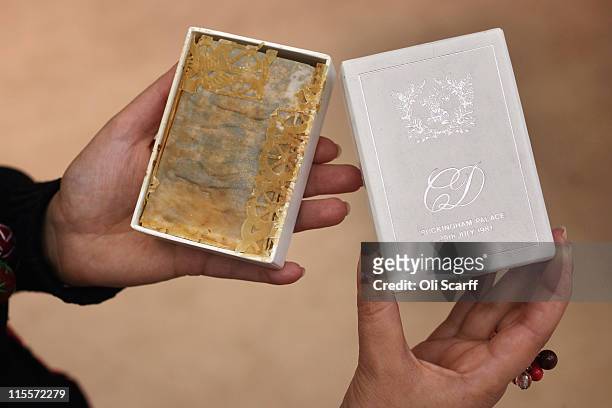 Woman holds a piece of wedding cake from the wedding of Prince Charles and Princess Diana in 1981 at the Olympia International Fine Art and Antiques...
