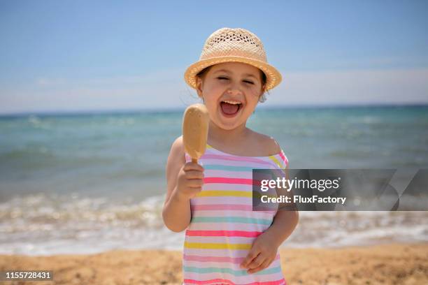 happy and joyful little girl eating ice cream on summer vacation - icecream beach stock pictures, royalty-free photos & images