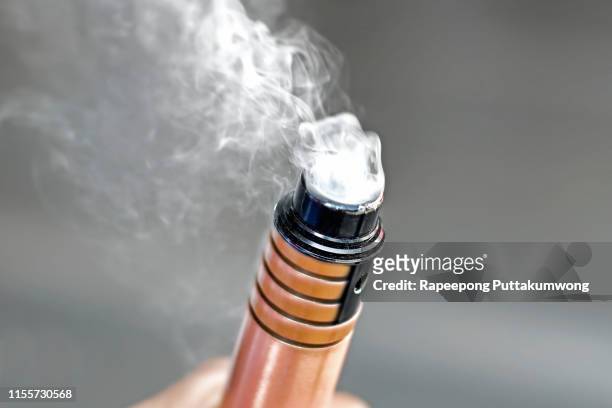 hand holding electronic cigarette - vape stock pictures, royalty-free photos & images