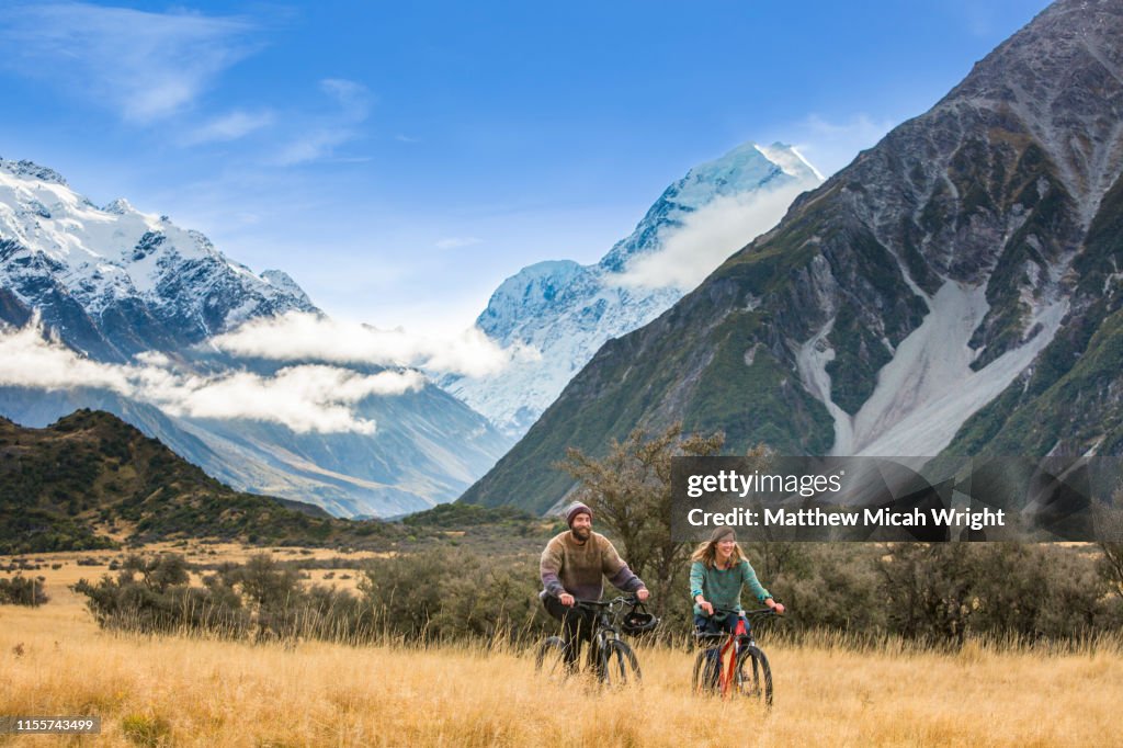 Friends ride bikes through the Mount Cook National Park.