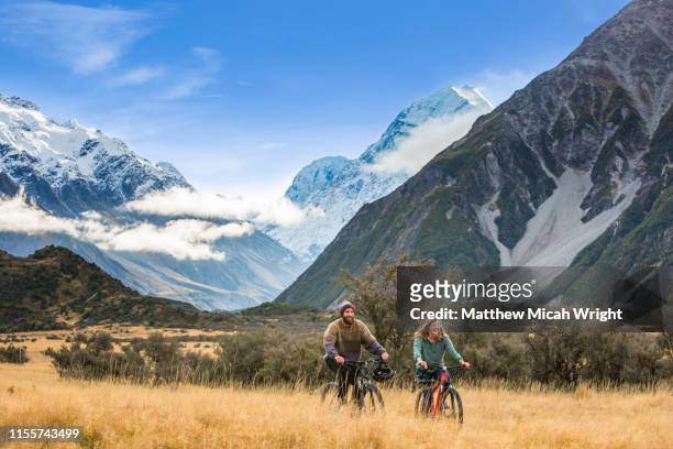 friends ride bikes through the mount cook national park. - new zealand stock pictures, royalty-free photos & images