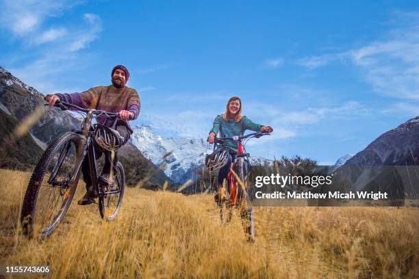 friends ride bikes through the mount cook national park. - matthew hale fotografías e imágenes de stock