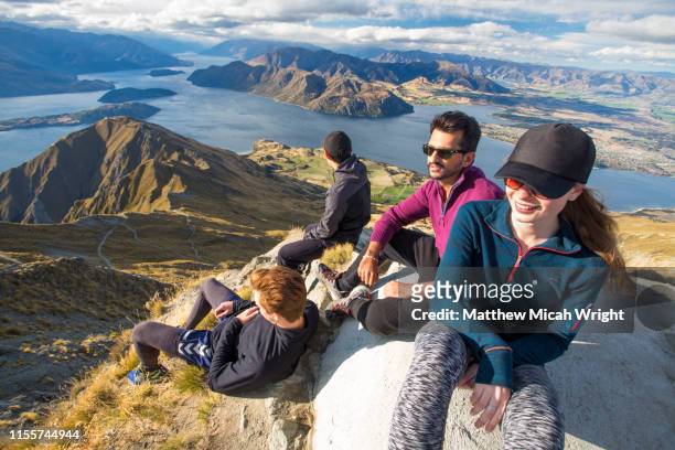 a group of hikers rest at the summit of roy's peak and enjoy the views. - bergsteiger gruppe stock-fotos und bilder
