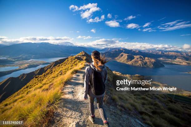 a woman walks down the trail on the roy's peak hike. - new zealand stock pictures, royalty-free photos & images