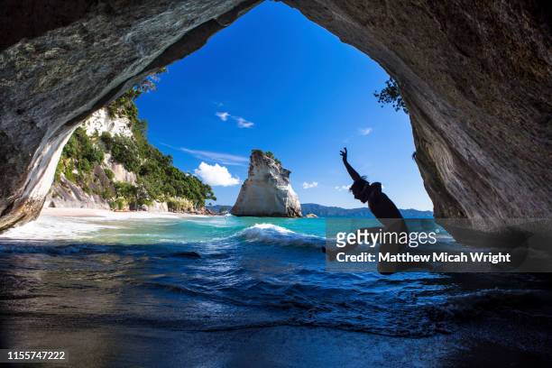 a silhouette of new zealand's famed cathedral cove and one of the most iconic landmarks in the country. - new zealand beach stock pictures, royalty-free photos & images