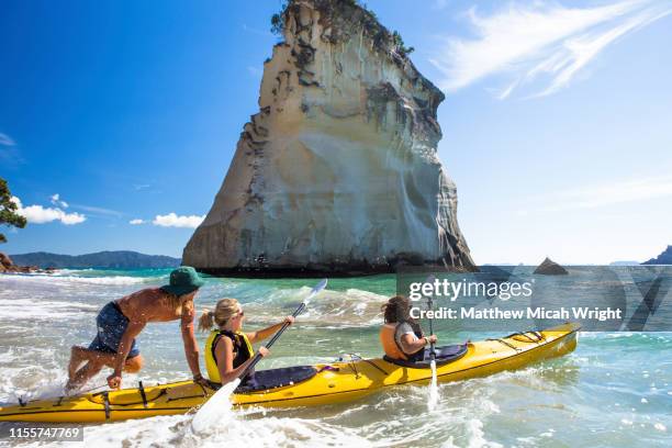 a kayak instructor pushes a kayak into the ocean - cathedral cove stock pictures, royalty-free photos & images