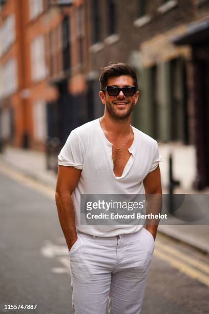Alex Mytton wears a white t-shirt, white pants, sunglasses, during London Fashion Week Men's June 2019 on June 09, 2019 in London, England.