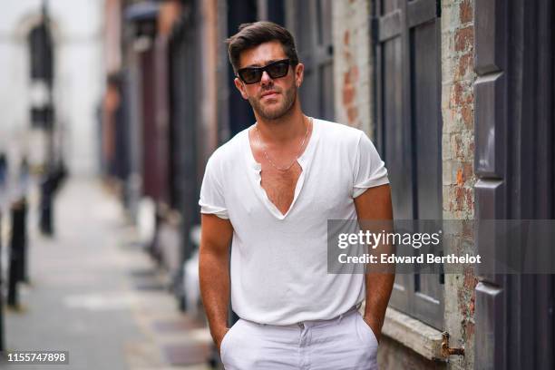 Alex Mytton wears a white t-shirt, white pants, sunglasses, during London Fashion Week Men's June 2019 on June 09, 2019 in London, England.