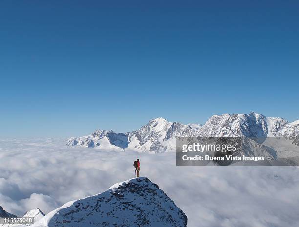 lone climber on top of a snowy peak - vetta foto e immagini stock