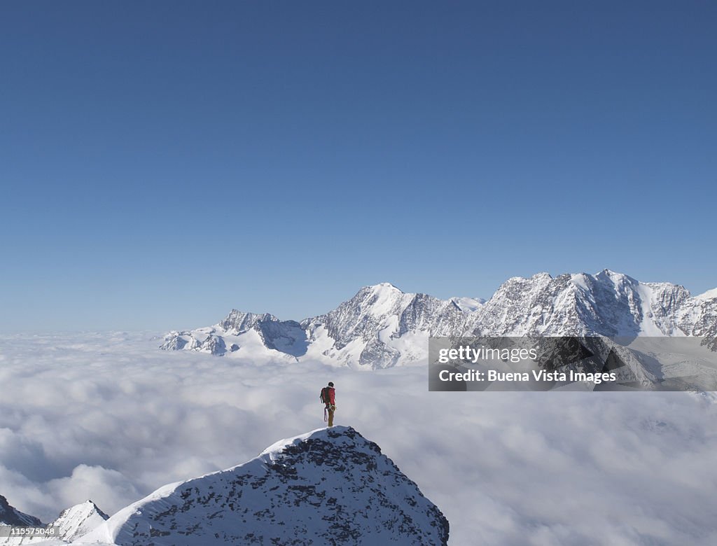 Lone climber on top of a snowy peak