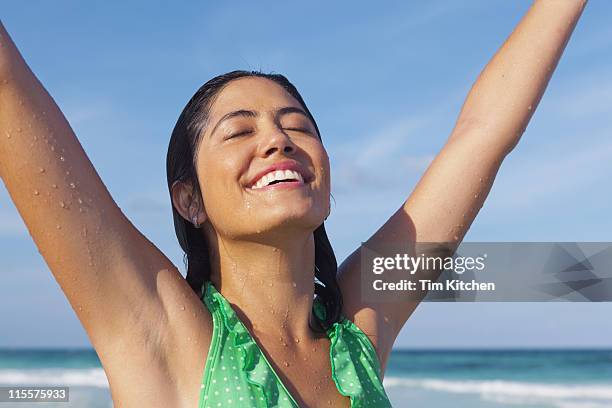 woman soaks sun's rays at beach, arms outstretched - arm sun beach stock-fotos und bilder