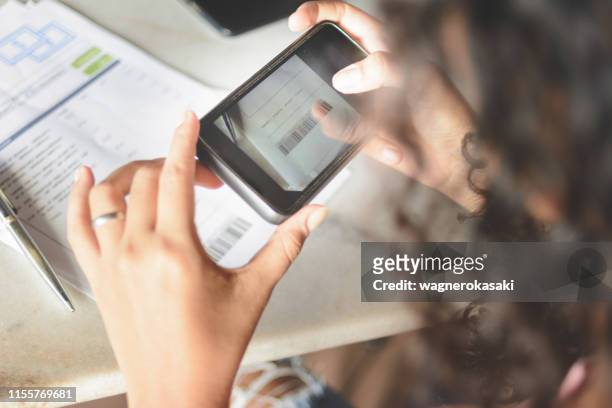 woman taking picture on smartphone of barcode for payment of bills via online banking app - deposit slip stock pictures, royalty-free photos & images