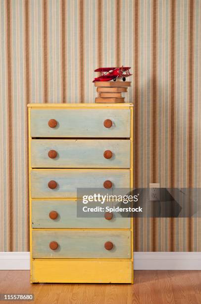 chest of drawers with books in empty bedroom - commode stockfoto's en -beelden