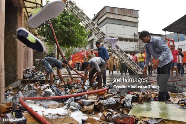 People try to find their belongings after a fire broke out in a shoe making factory, at Lawrence Road Industrial Area on July 15, 2019 in New Delhi,...