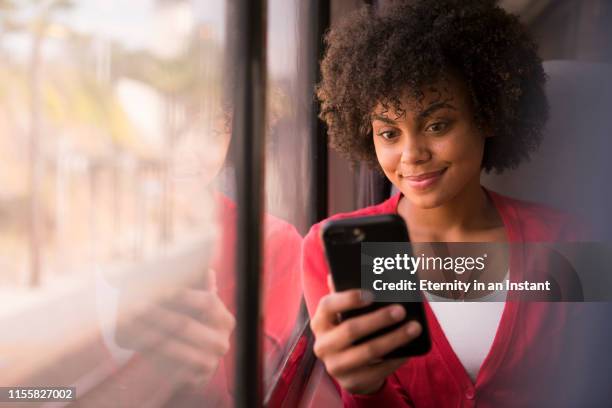 portrait young woman sitting on a train - smartphone im zug stock-fotos und bilder