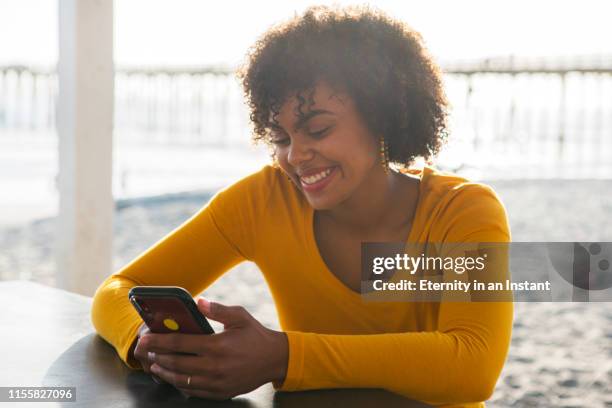 young woman using her phone outdoors - young teen girl beach ストックフォトと画像