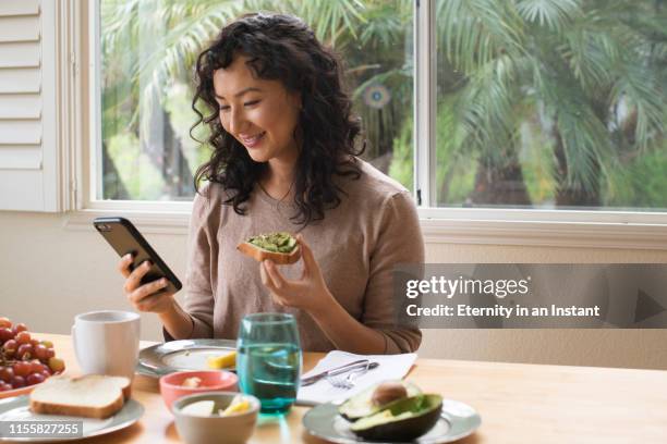 young asian woman eating a healthy breakfast - woman eating toast photos et images de collection