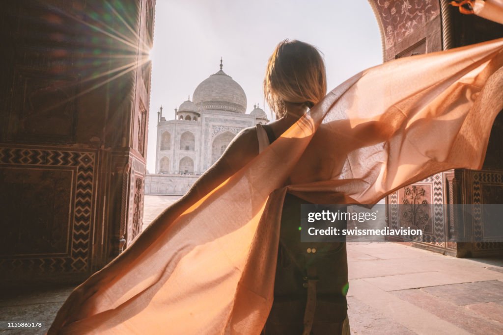 Gelukkige jonge vrouw wandelen en dwalen in de beroemde Taj Mahal bij Sunrise Holding sjaal in handen, Agra, India. People Travel Asia concept
