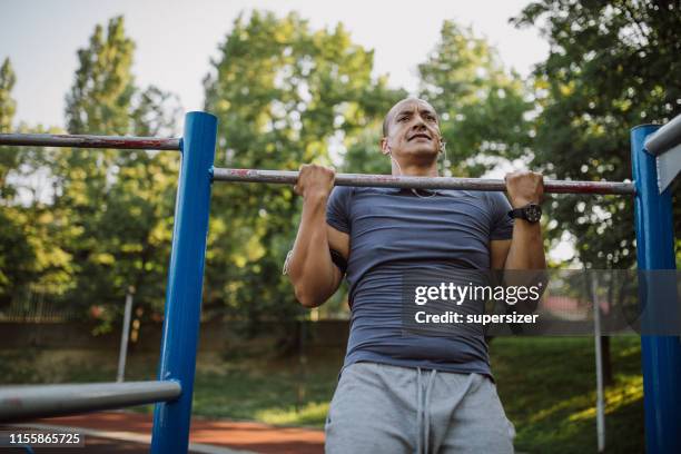 one latin man exercising in the park - chin ups stock pictures, royalty-free photos & images