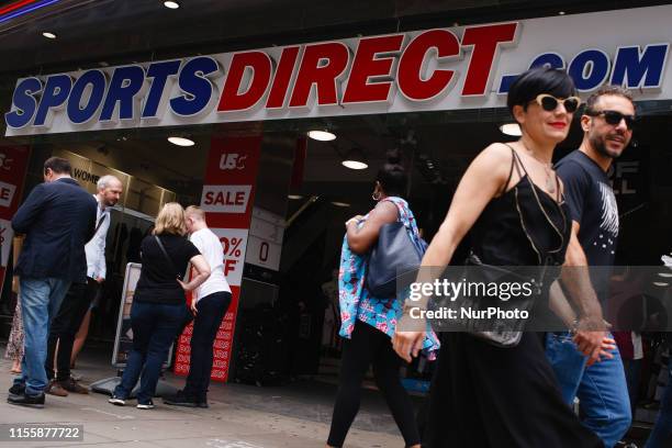 Shoppers walk past a branch of sporting goods retailer Sports Direct, owned by high street tycoon Mike Ashley, on Oxford Street in London, England,...