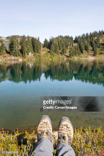 hiking boots in front of tranquil alpine tarn, b.c., canada. - feet selfie woman stockfoto's en -beelden
