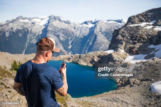 mountaineer views the climbing route using a gps device. - garmin-global-positioning-system stock pictures, royalty-free photos & images