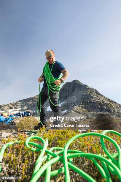 low angle view of a climber coiling his safety rope. - wildlife reserve stock pictures, royalty-free photos & images