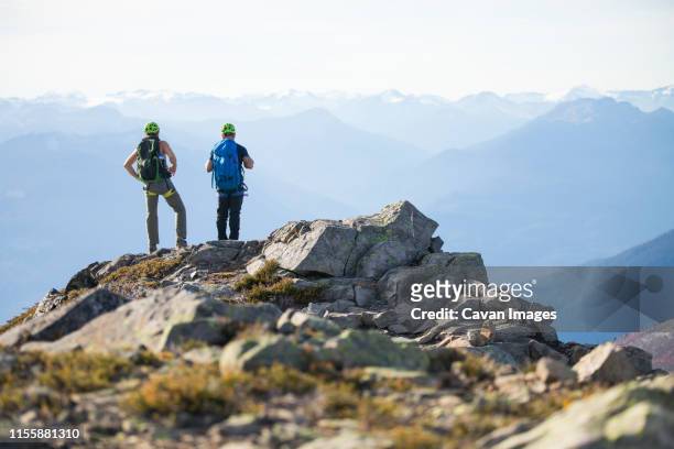 two climbers stand on the summit of douglas peak, british columbia. - team climbing up to mountain top stockfoto's en -beelden