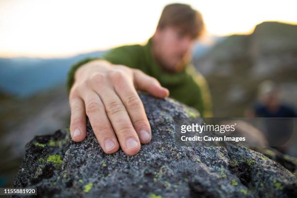 climbers hand grips a rock at the top of a bouldering route. - stone hand stock-fotos und bilder