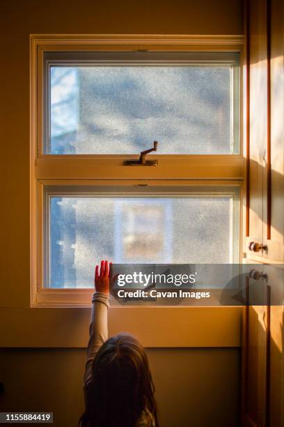 a small child reaches her hand up to sunlight streaming through window - sun rays through window stock pictures, royalty-free photos & images