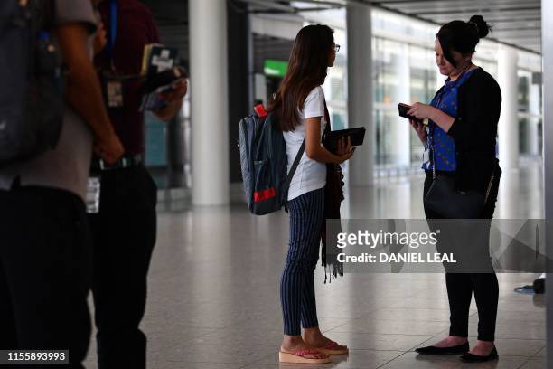 Official checks the passport of a passenger recently arrived from Mumbai in India in Terminal 2 at Heathrow Airport in London on July 16 part of...