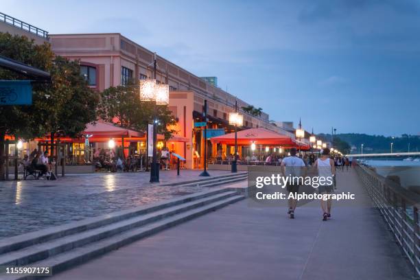 tourists beside the garonne river at bordeaux with the pont jacques chaban-delmas bridge - garonne stock pictures, royalty-free photos & images