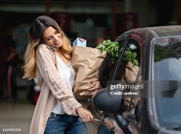 frau multitasking immer in das auto nach dem einkaufen im lebensmittelgeschäft - woman entering home stock-fotos und bilder