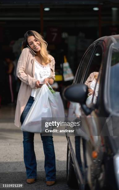 happy woman walking to the car after shopping at the supermarket - plastic bag stock pictures, royalty-free photos & images
