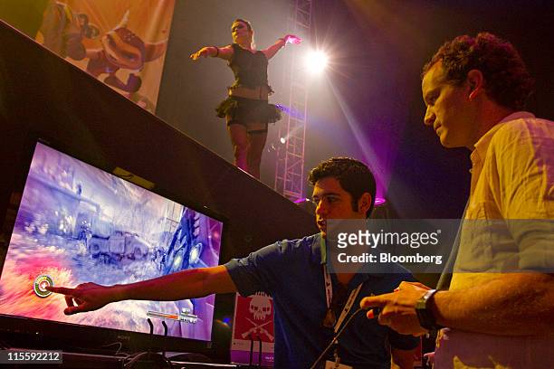 Gamer demonstrates Sony Computer Entertainment's "Resistance 3" video game while a dancer performs on stage during the Electronic Entertainment Expo...