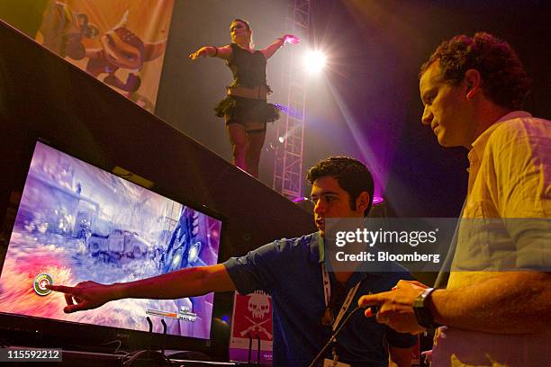 Gamer demonstrates Sony Computer Entertainment's "Resistance 3" video game while a dancer performs on stage during the Electronic Entertainment Expo...