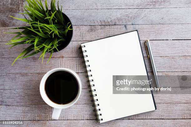 green plant, blank notebook and pen - schreibtisch bücher stock-fotos und bilder