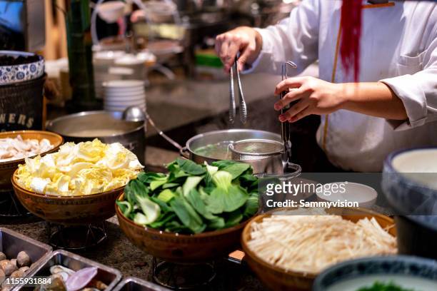 the cook is cooking boiled noodles and vegetables - chinese soup photos et images de collection