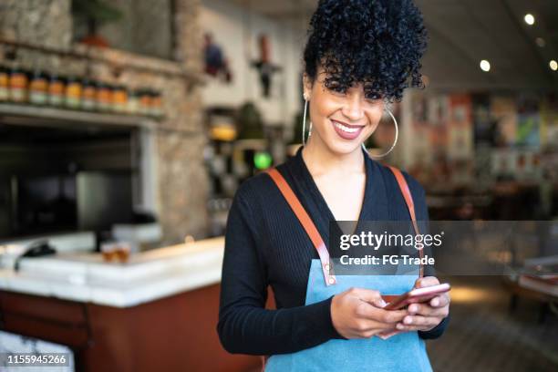 portret van ondernemer met behulp van telefoon en kijken naar camera - catering black uniform stockfoto's en -beelden