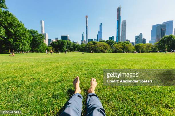 personal perspective of a man relaxing barefoot in central park, new york city - city from a new angle stockfoto's en -beelden