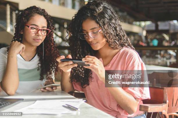 Two young women taking picture on smartphone of barcode for payment of bills via online banking app