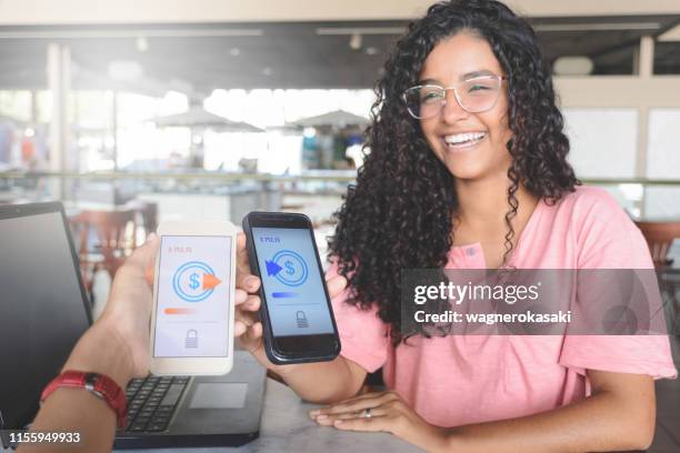 junge frauen, die geld über digitale brieftasche senden, mit drahtloser technologie - tauschen stock-fotos und bilder