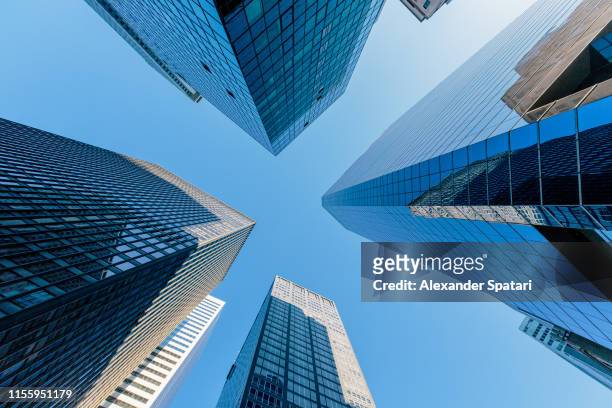 low angle view of modern skyscrapers against clear blue sky in manhattan downtown, new york - grattacielo foto e immagini stock