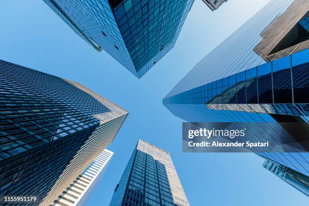 low angle view of modern skyscrapers against clear blue sky in manhattan downtown, new york - blue corporate imagens e fotografias de stock