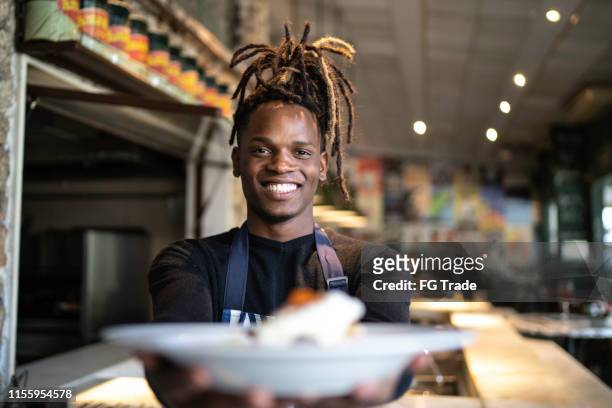 smiling male chef holding prepared dish at restaurant - cooking show stock pictures, royalty-free photos & images
