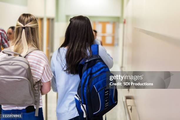 rear view of two friends walking to class - female high school student stock pictures, royalty-free photos & images