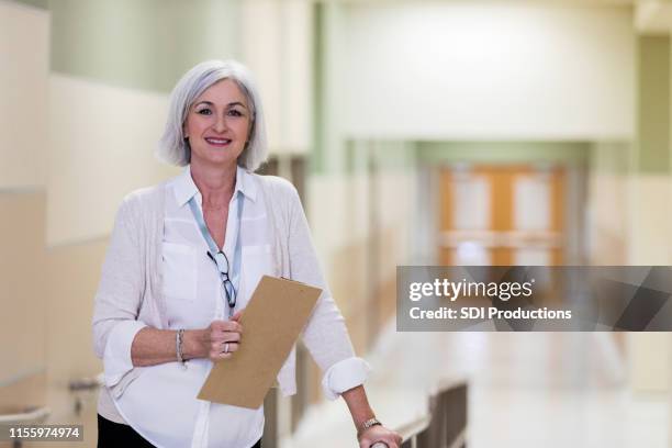 volwassen school counselor neemt pauze in de gang - administrative professionals stockfoto's en -beelden