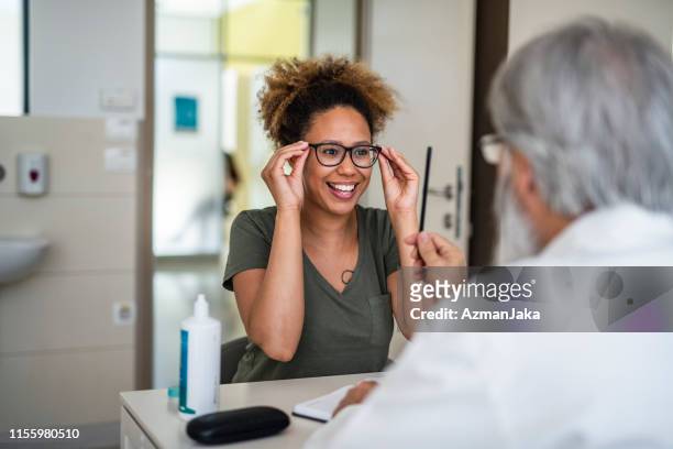 mulher que testa para fora seus eyeglasses novos no escritório da oftalmologia - optometry - fotografias e filmes do acervo