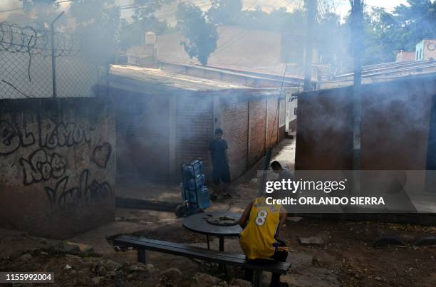 Residents wait outside their homes during a fumigation operation to combat Aedes aegypti, vector of the dengue fever, in Tegucigalpa on July 16,...