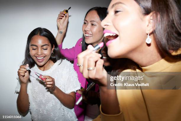 cheerful friends doing make-up at home - applying lipstick ストックフォトと画像